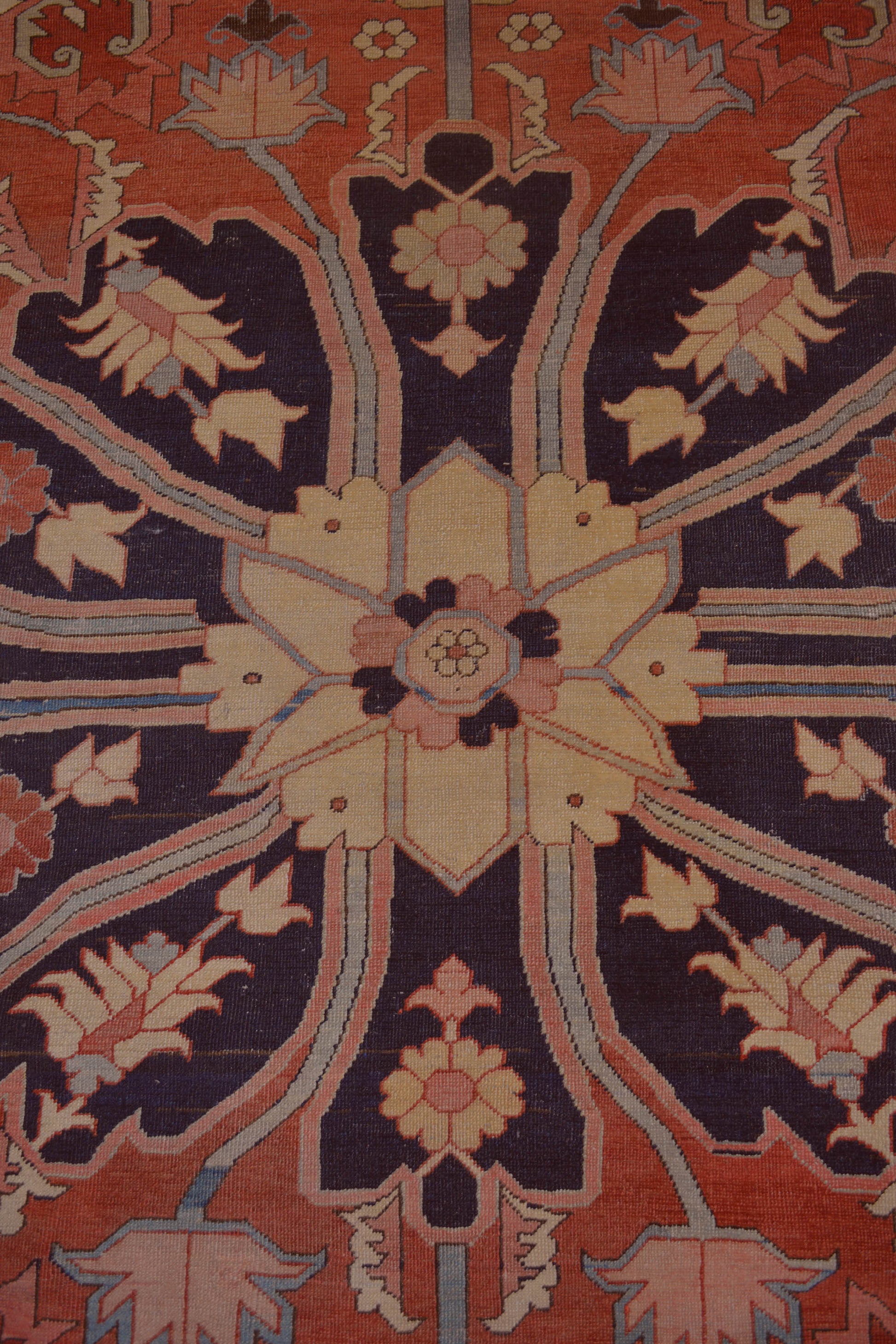 The central focal area has a large black flower holding a secondary beige flower in the middle, and the same design is placed in each corner of the central area of ​​the rug.