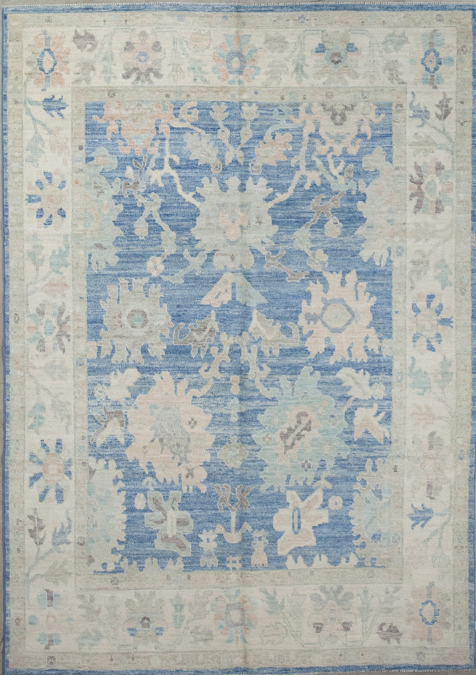 Skyish carpet knitted with the vibe coming from the atmosphere. The color scheme has blue variations, beige, gray, and pinkish accents.