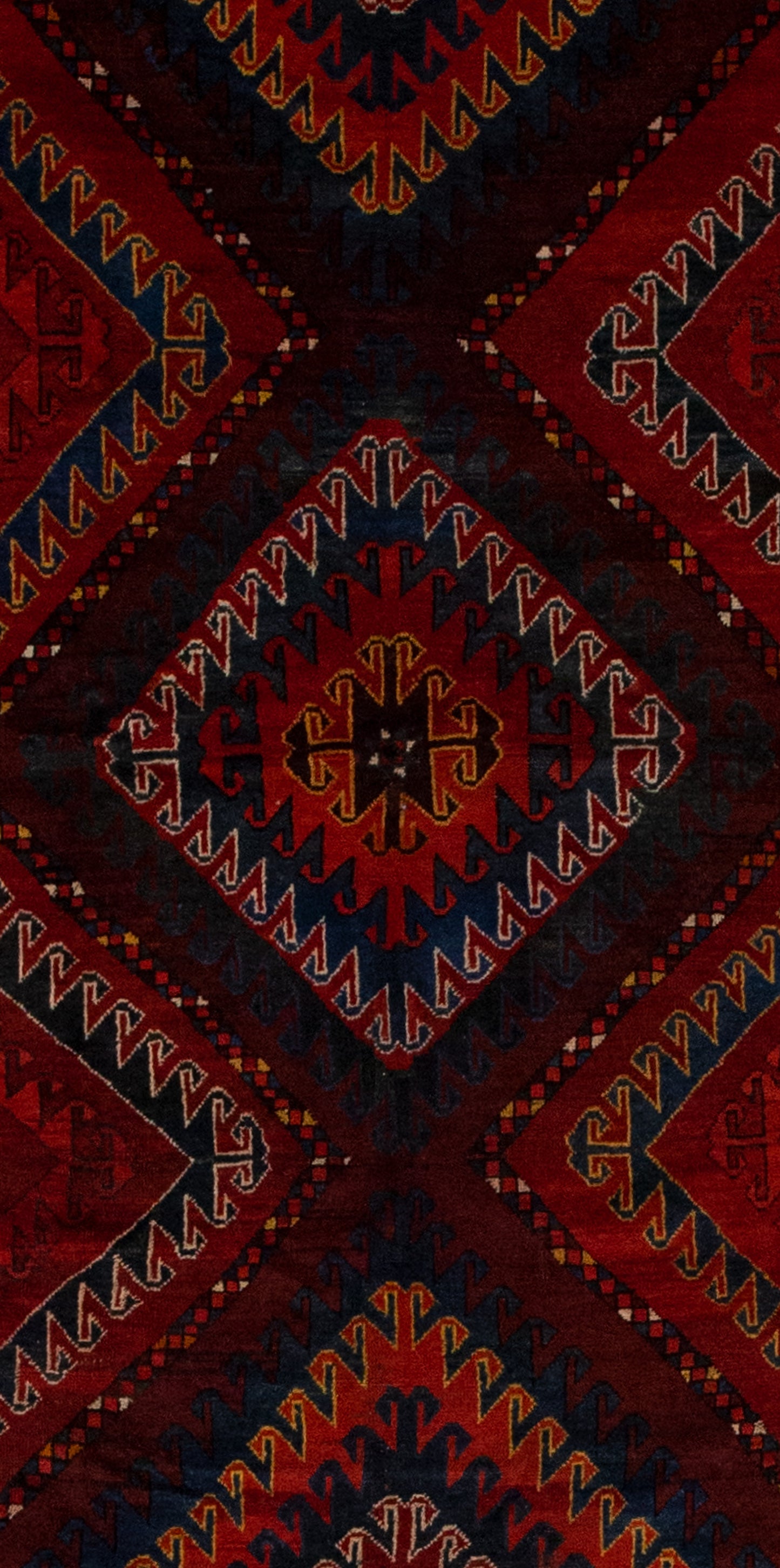 The center of the rug features three large outlined rhombuses with nested rhombuses outlined with wave patterns in different colors.