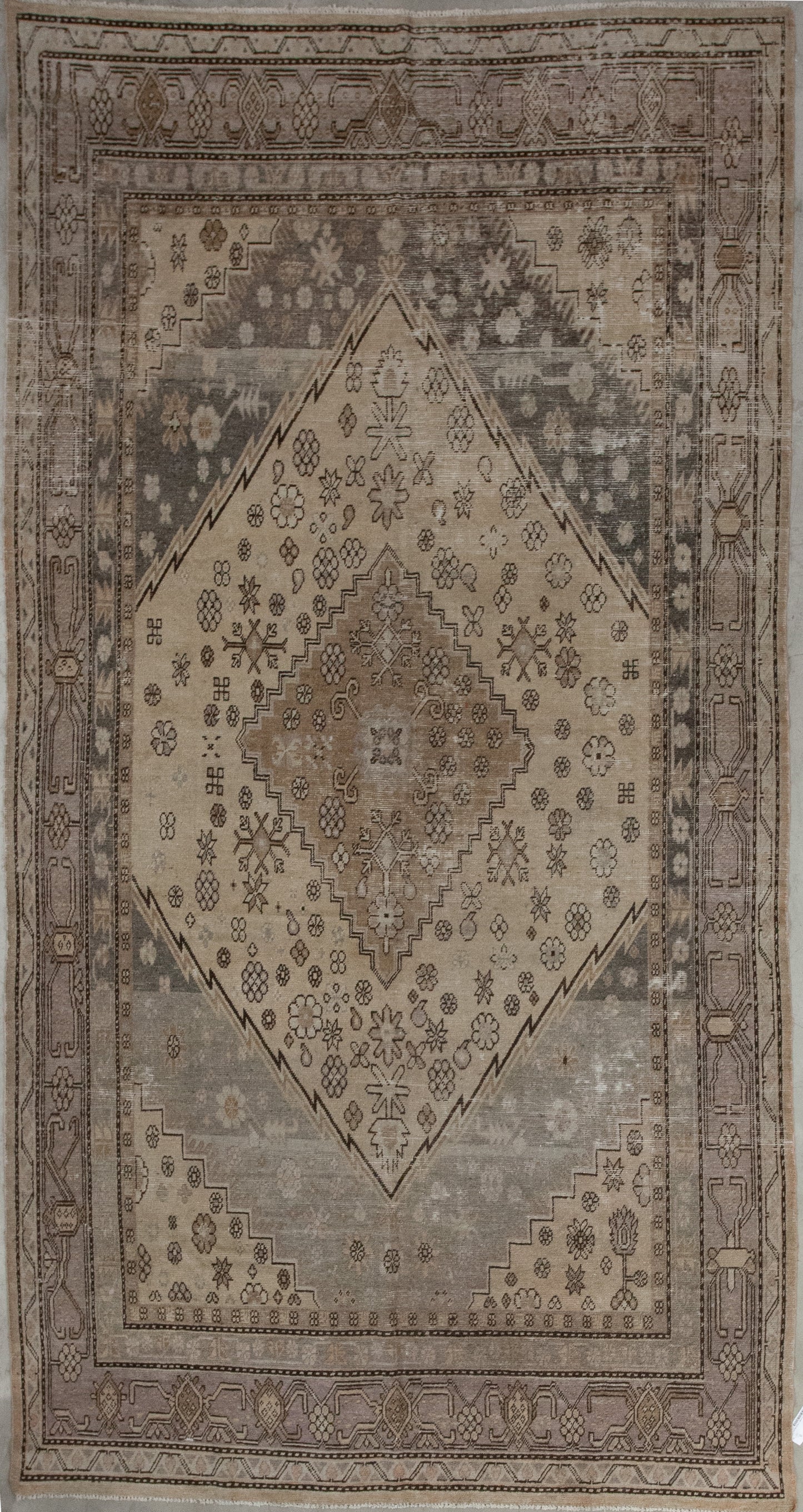 This conservative carpet was woven within a calm and relaxing color hue with variations of beige. The main design features a large diamond shape in the center with a nested smaller one.