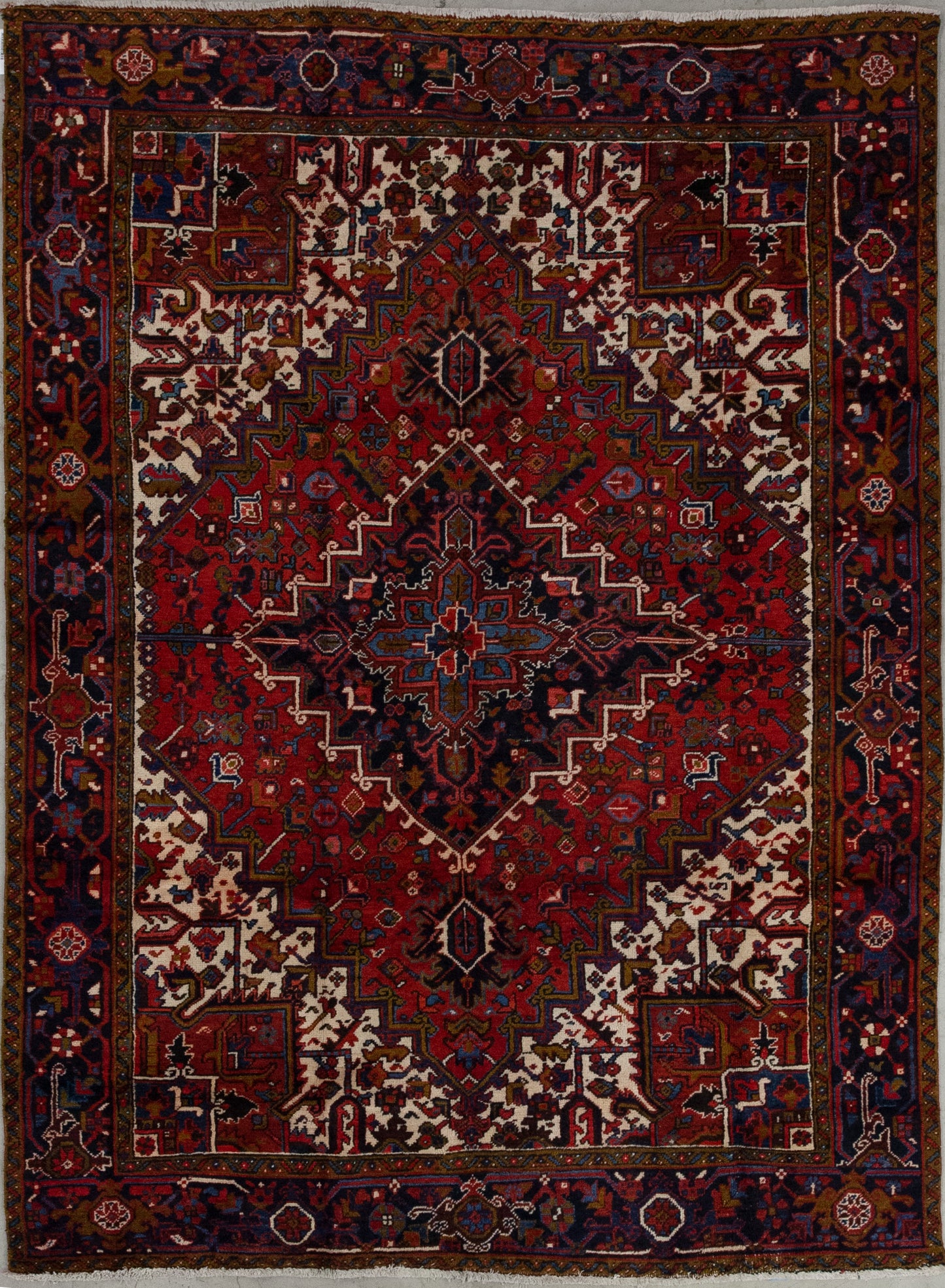 This remarkable rug comes with a fiery color combination to evoke passion wherever you lay it down. The colors of the carpet are red as the dominant tone, olive green, variations of blue, black, and white. The artwork features a large red rhomb which is nesting two more, and all of them are patterned with abstract types of flowers and leaves.