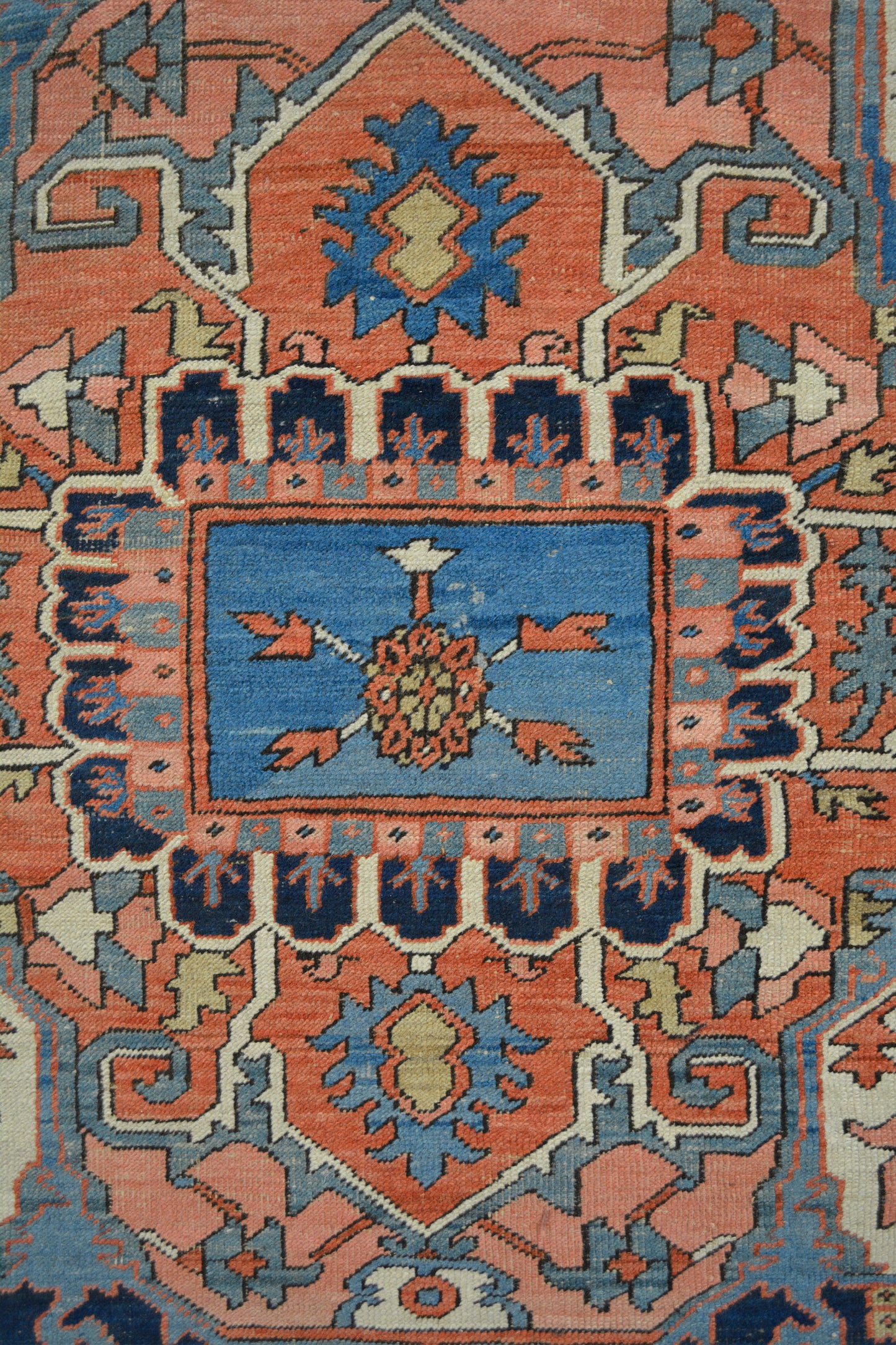 The rug's close-up shows a small design with five arrows pointing to the center over blue background to create contrast.