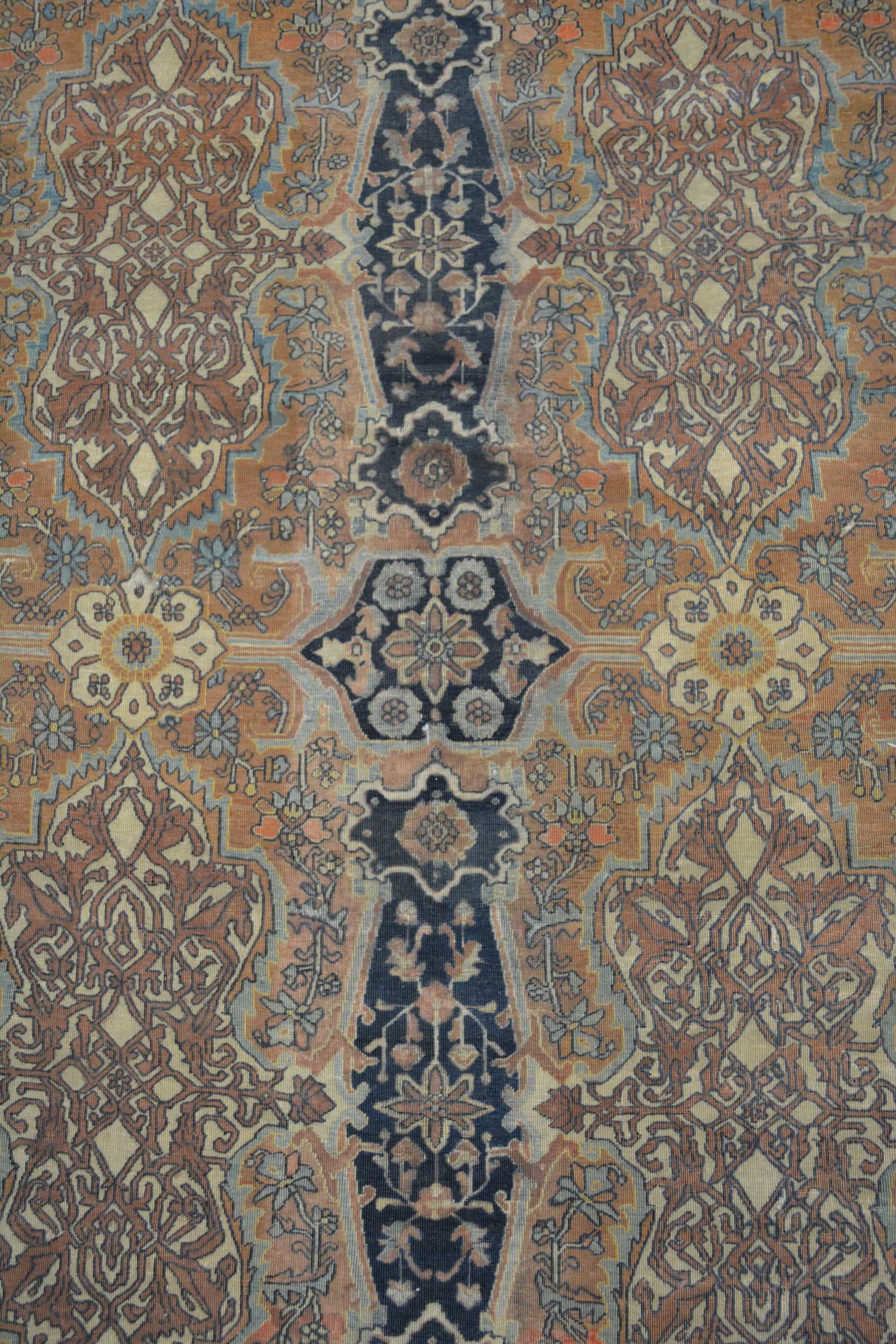 The center of the rug is packed with tiny flowers, branches and small geometrical details. All the pattern is arranged symmetrically.