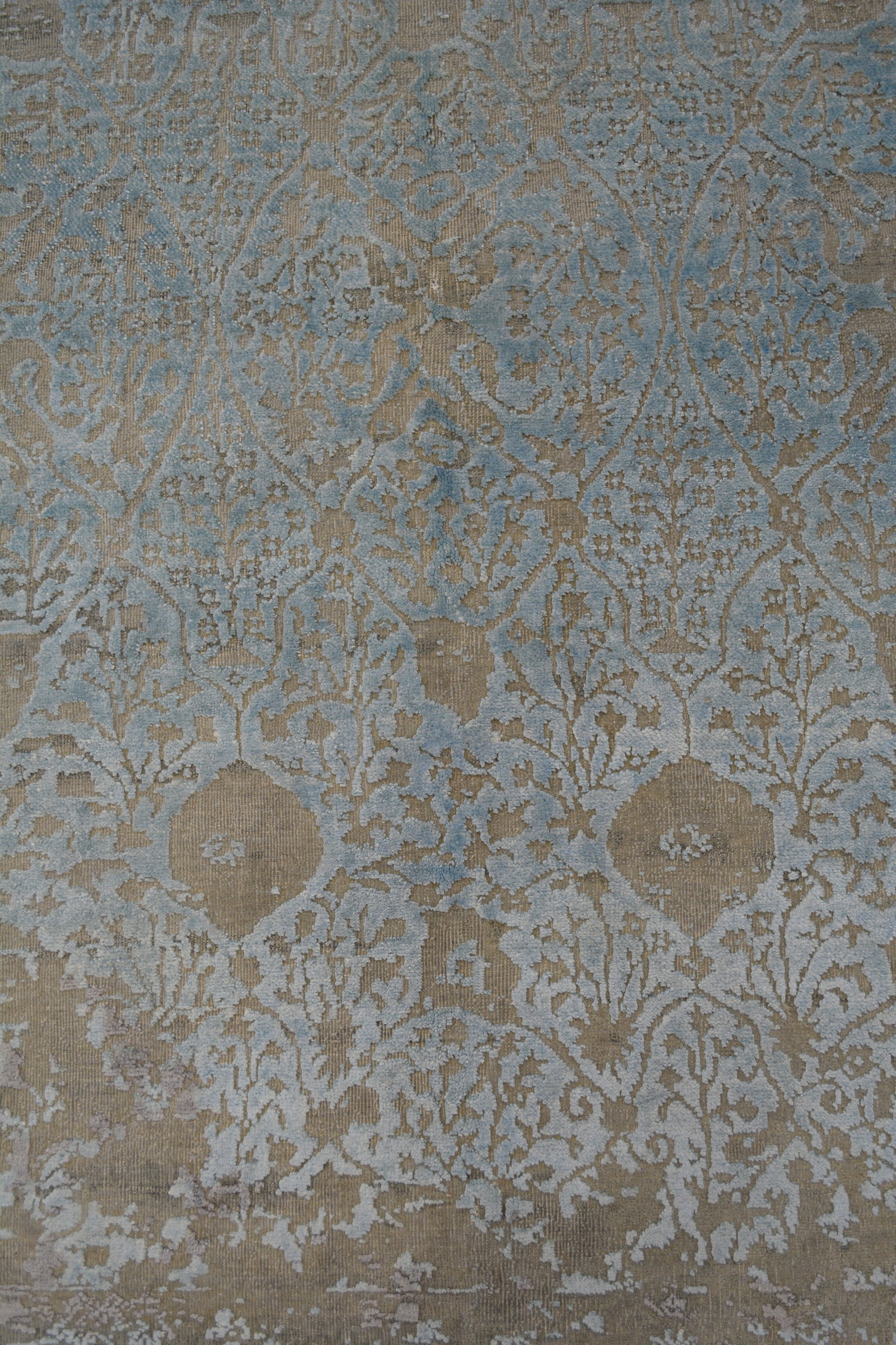 in the center of the rug, there is a gradient from a bottom white to top light blue with a climbing branches as a pattern.