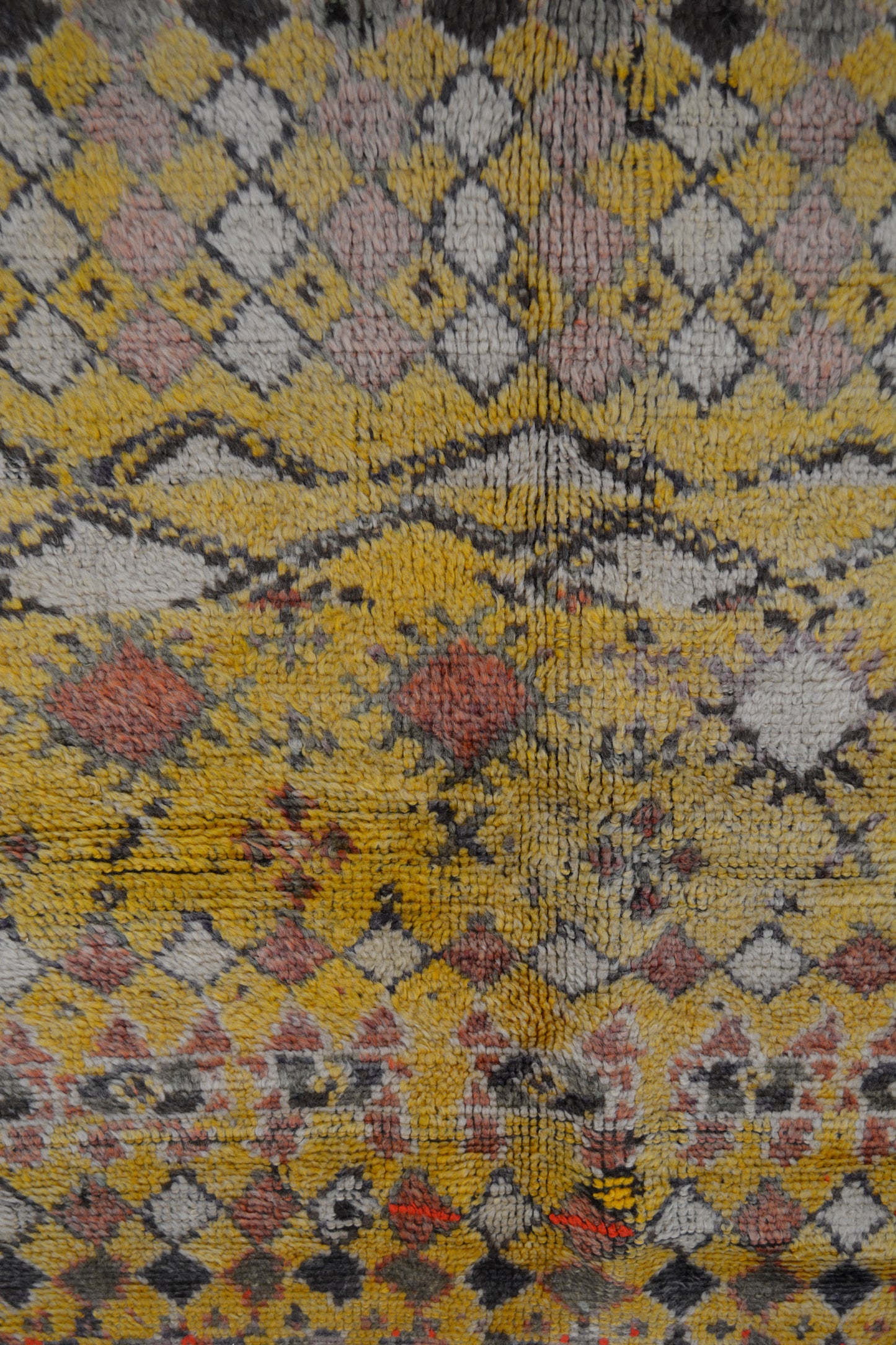 the close up of the center of the rug shows a rhombuses pattern in white, pink, red, and black.