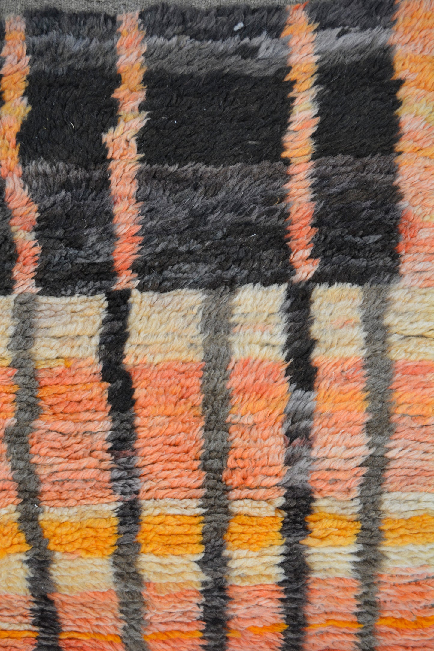 The rug's color palette has orange, black, yellow, and beige.