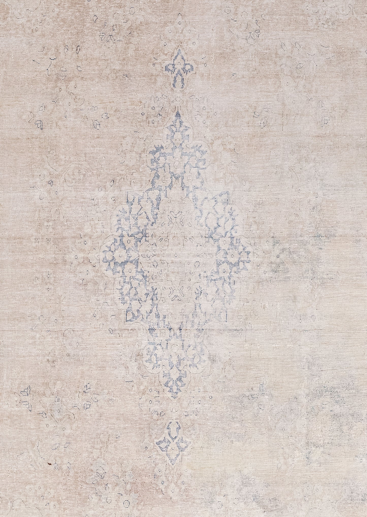 The close-up of the carpet offers a deeper look at the blue diamond shape that has a nested beige one, and each element of the rug has been woven symmetrically.