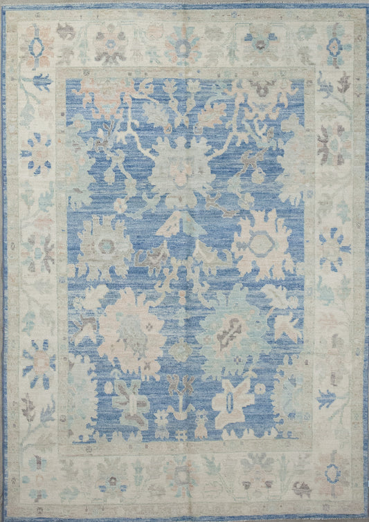 Skyish carpet knitted with the vibe coming from the atmosphere. The color scheme has blue variations, beige, gray, and pinkish accents. 