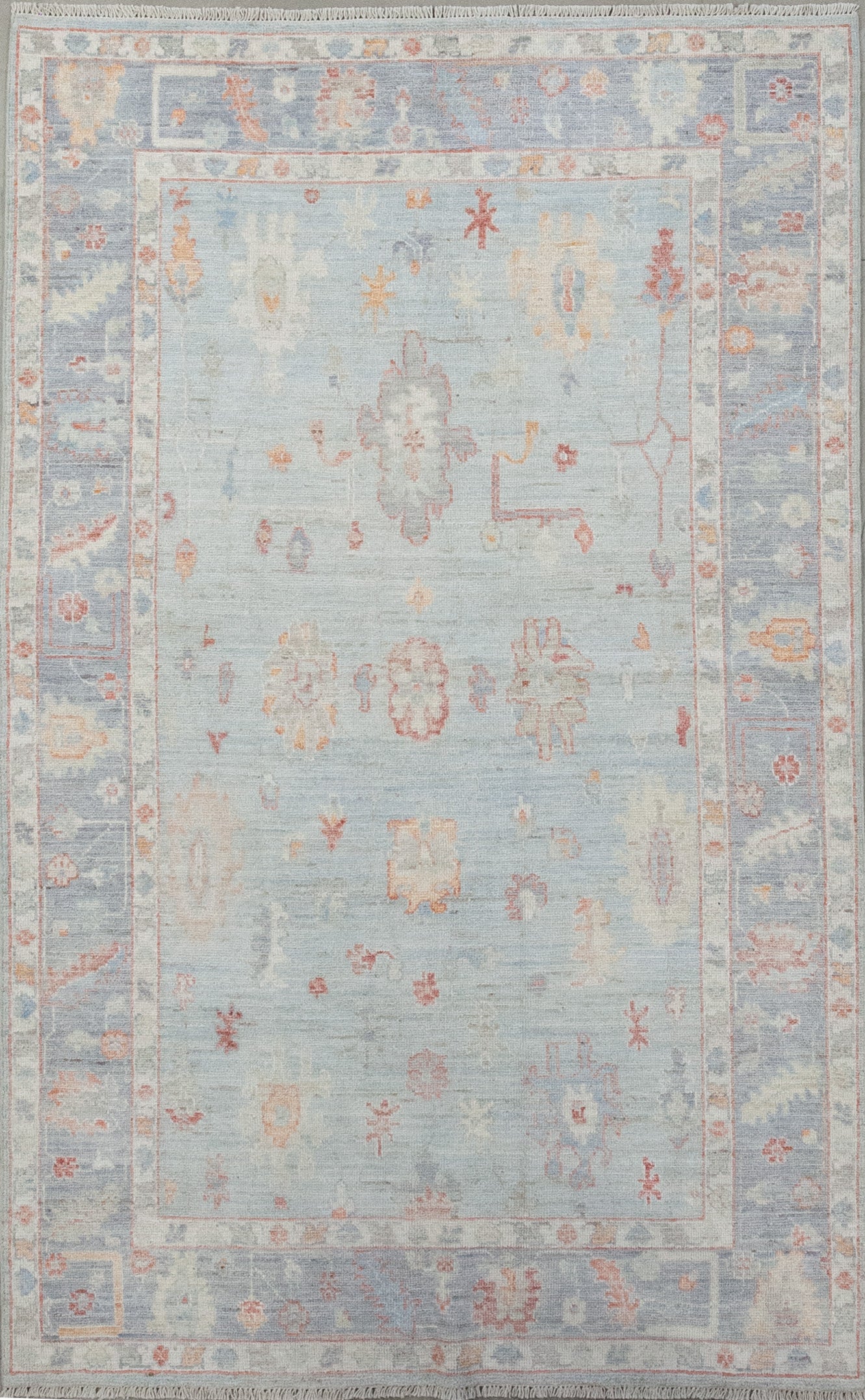 A sophisticated rug was woven in shades of blue as the dominant color, plus orange, red and white as contrast. The design features abstract red and white poppies, sunflowers, with branches all around it.