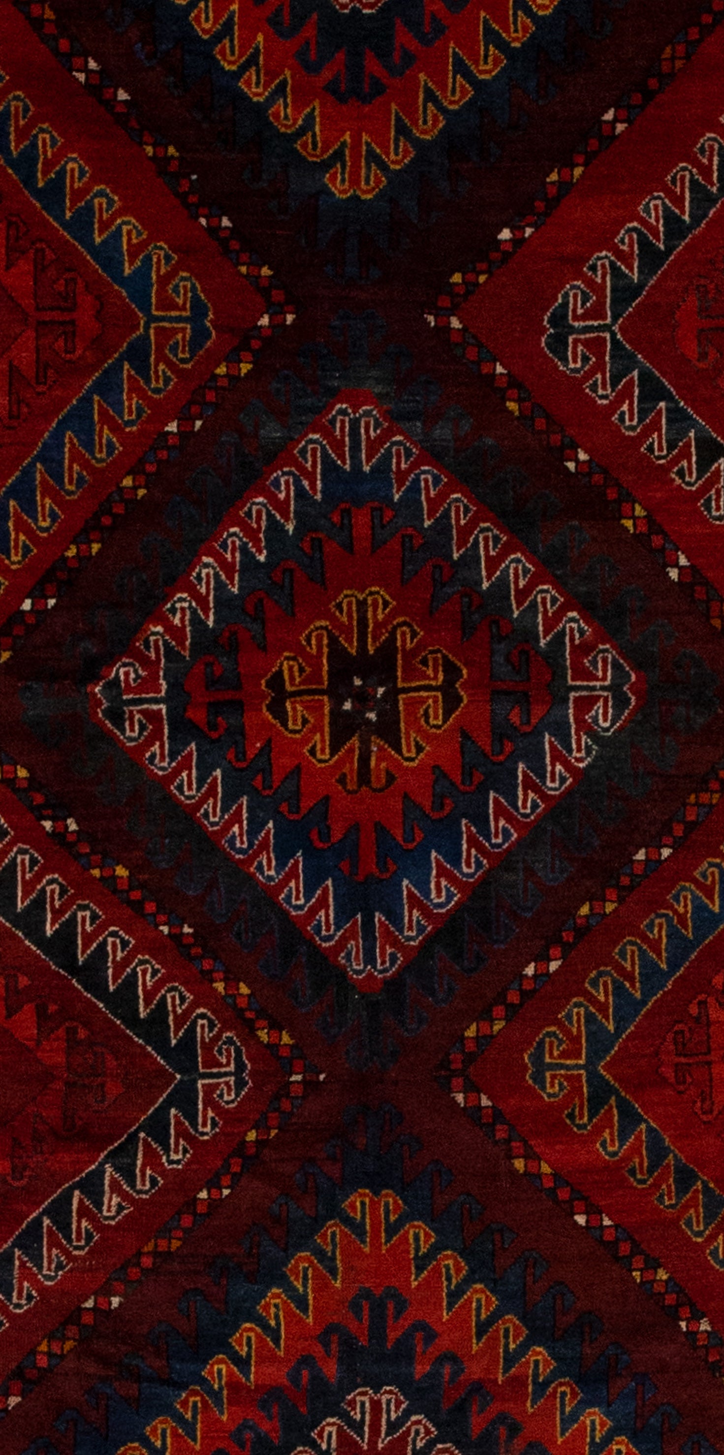 The center of the rug features three large outlined rhombuses with nested rhombuses outlined with wave patterns in different colors. 