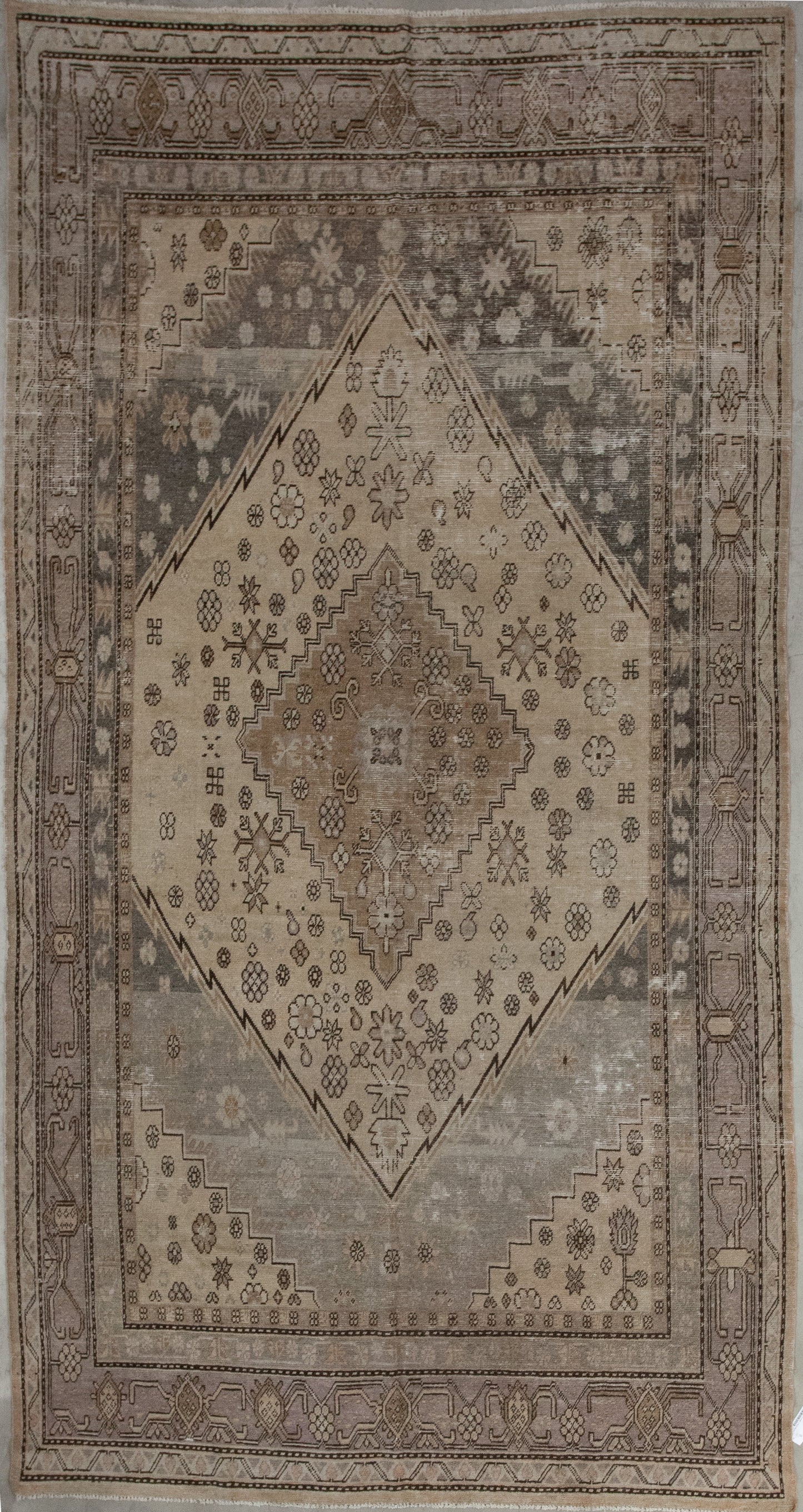 This conservative carpet was woven within a calm and relaxing color hue with variations of beige. The main design features a large diamond shape in the center with a nested smaller one. 