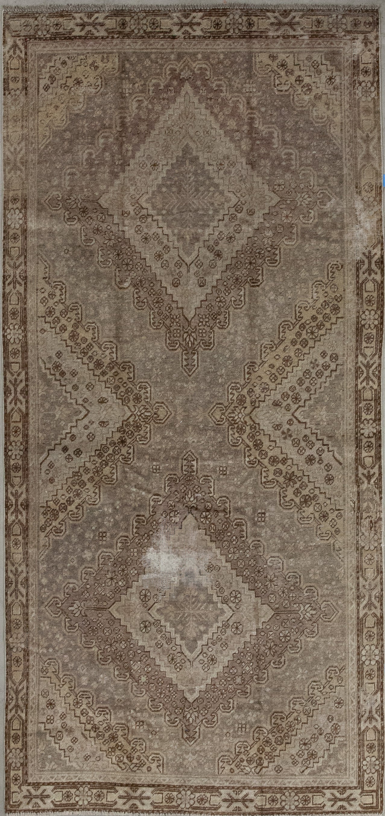 This classic carpet comes in a duo-tone color scheme which shows variations of brown and beige. The art composition features two large diamond shapes with four nested rhombuses which are all patterned.