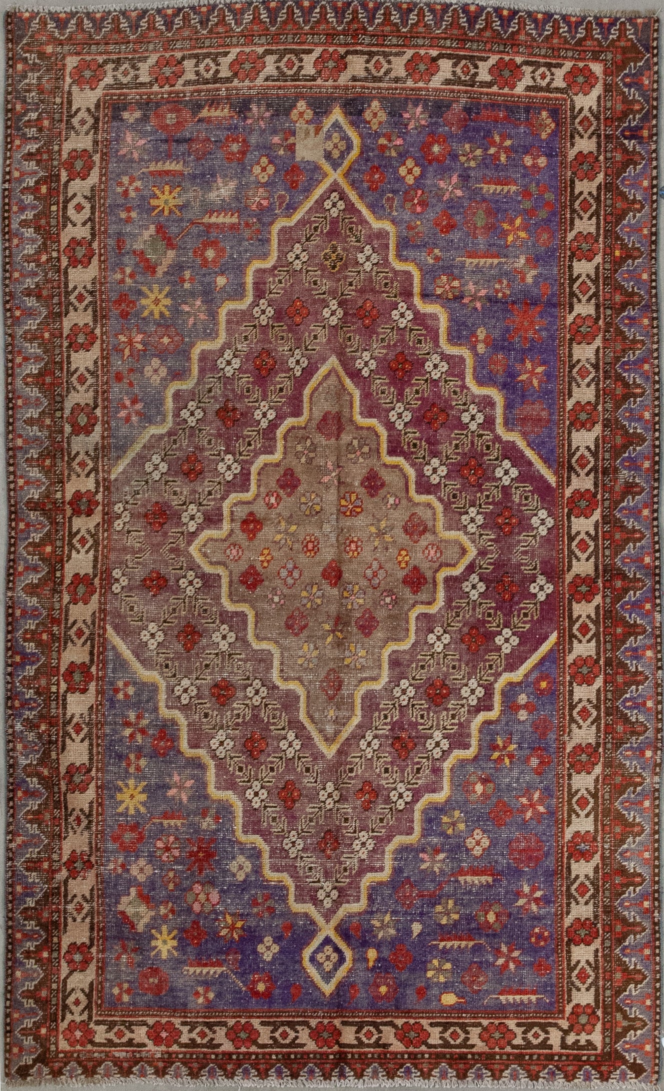 This wonderful carpet was woven with a joyful color scheme which has blue, burgundy, brown, yellow, red, and white. The main design features a large central rhomb holding a nested one, and both shapes contain a flowers pattern.