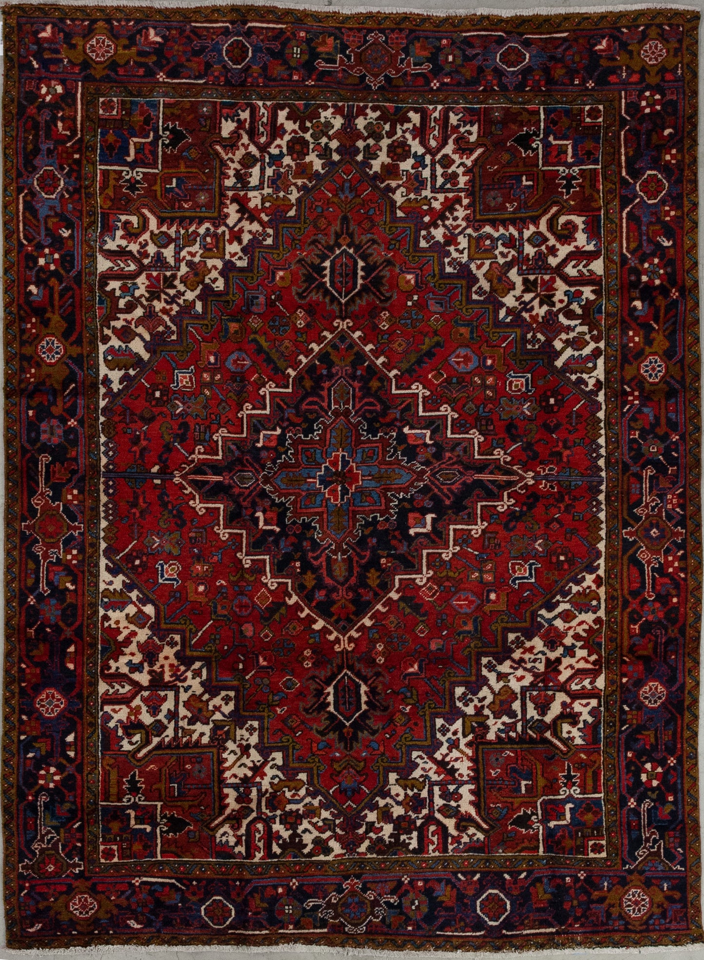 This remarkable rug comes with a fiery color combination to evoke passion wherever you lay it down. The colors of the carpet are red as the dominant tone, olive green, variations of blue, black, and white. The artwork features a large red rhomb which is nesting two more, and all of them are patterned with abstract types of flowers and leaves.